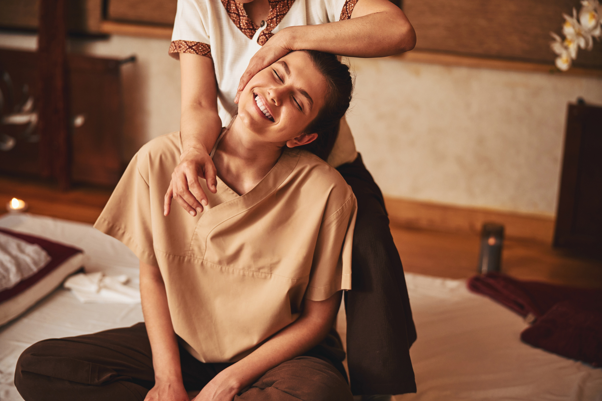 Massagist tilting woman head while pressing elbow to her shoulder